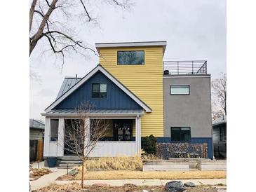 Unique two-story home with a yellow exterior, a rooftop deck, and manicured lawn at 4428 Perry St, Denver, CO 80212