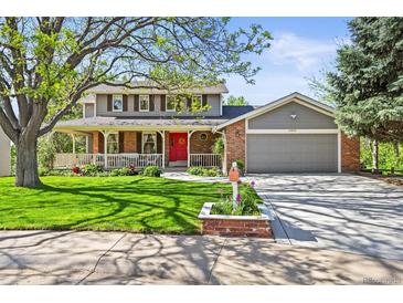 Charming two-story home with a landscaped front yard, covered porch, and inviting red front door at 6862 Independence Ct, Arvada, CO 80004