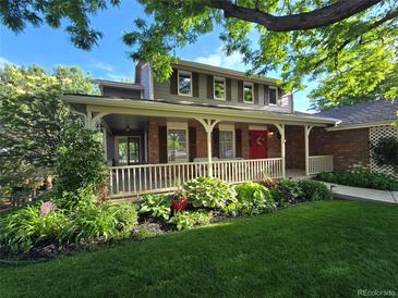 Charming home featuring a landscaped front yard, inviting porch, and a vibrant red front door at 6862 Independence Ct, Arvada, CO 80004