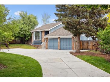 Charming blue two-story home with brick accents, a well-manicured lawn, and a long concrete driveway at 8174 Dudley Cir, Arvada, CO 80005