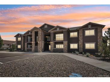 Modern apartment building with stone accents and a well-maintained parking area at sunset at 875 E 78Th Ave # 72, Denver, CO 80229