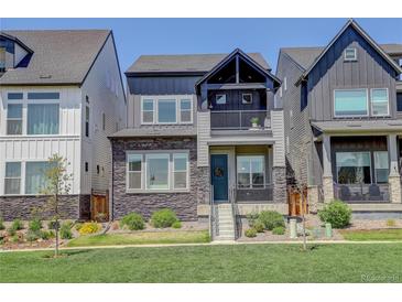 Charming two-story home featuring stone accents, a small balcony, and a well-manicured lawn at 16550 Umatilla Pl, Broomfield, CO 80023