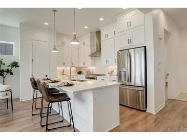 Bright kitchen features white cabinets, stainless steel appliances, and a large quartz island with seating at 16550 Umatilla Pl, Broomfield, CO 80023