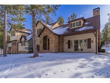 Stunning two-story home with stone accents and snowy landscape at 590 Cumberland Rd, Larkspur, CO 80118