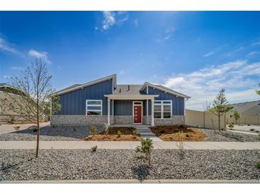 Charming home featuring a blue exterior, stone accents, landscaped front yard and a pop of color with the red front door at 5150 N Quemoy Ct, Aurora, CO 80019