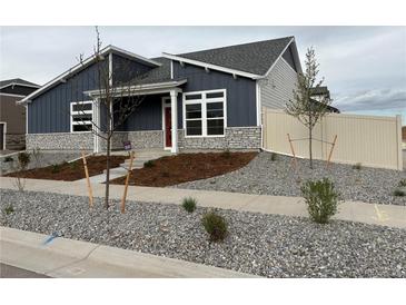 Charming single Gathering home with a well-manicured lawn, stone accents and a red front door at 5150 N Quemoy Ct, Aurora, CO 80019