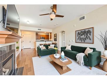 Bright living room featuring stylish green sofas, a ceiling fan, and wood flooring at 9019 E Panorama Cir # D207, Englewood, CO 80112