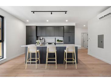 Modern kitchen with a large island, sleek dark cabinetry, and stainless steel appliances at 1601 Park Ave # 307, Denver, CO 80218