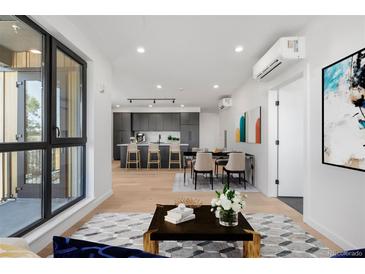 Open-concept living area with hardwood floors, modern kitchen, dining space, and large windows providing ample natural light at 1601 Park Ave # 307, Denver, CO 80218