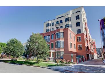 Modern multi-story condo building featuring brick accents and a well-maintained landscape under a clear, blue sky at 410 Acoma St # 212, Denver, CO 80204