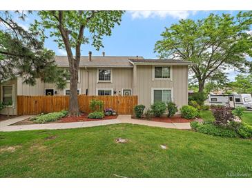 Charming townhome featuring a well-manicured lawn, wood fence, and lush trees, creating a welcoming curb appeal at 6936 S Knolls Way, Centennial, CO 80122