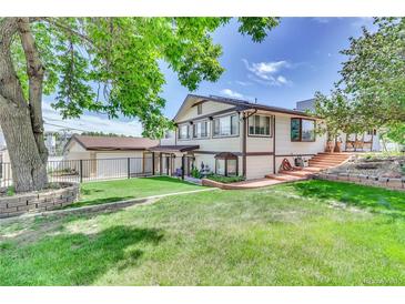 Ranch style home with landscaped yard, detached garage, and spacious backyard at 7475 W Kentucky Ave, Lakewood, CO 80226