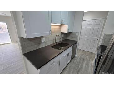 Updated kitchen features white cabinets, gray countertops, and stainless steel appliances at 100 E Highline Cir # 307, Centennial, CO 80122