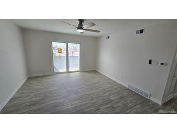 Bright living room featuring wood-look floors, ceiling fan, and sliding glass doors to outdoor space at 100 E Highline Cir # 307, Centennial, CO 80122