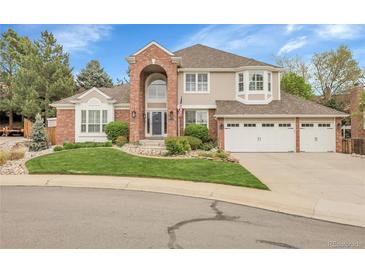 Charming two-story home with a brick facade, arched entryway, three-car garage, and well-manicured front yard at 4220 S Yarrow Ct, Lakewood, CO 80235