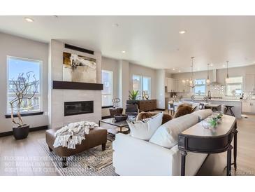 Bright, open living room featuring a modern fireplace, stylish decor, and hardwood floors leading into the kitchen at 1768 Peak Loop, Broomfield, CO 80023