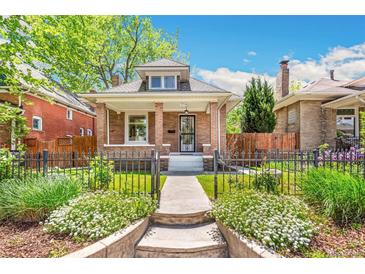 Charming brick home with well-manicured lawn, inviting front porch, and wrought iron fence at 2738 W 38Th Ave, Denver, CO 80211