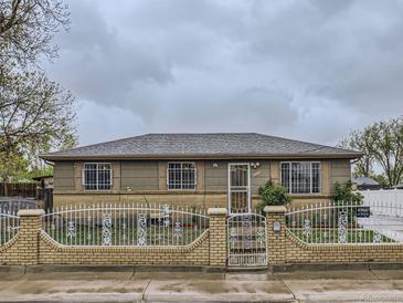Charming single-story home with a brick and wrought iron fence on a cloudy day at 5481 Xanadu St, Denver, CO 80239