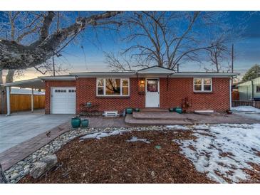 Brick ranch home with attached garage, landscaping, and covered carport at 5107 Johnson St, Arvada, CO 80002