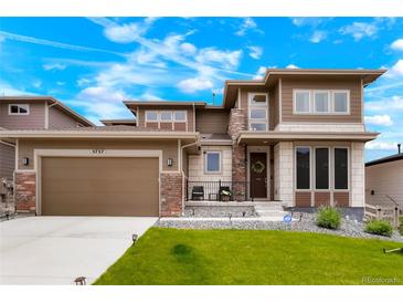Inviting two-story home featuring a manicured lawn, stone accents, and attached two car garage at 5737 Amarosa Dr, Parker, CO 80134