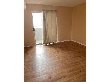 Bright living room with wood-look floors and sliding door to balcony at 5775 W Atlantic Pl # 103, Lakewood, CO 80227