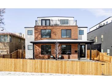Modern brick home with a rooftop deck and a well-manicured lawn. The wooden fence adds charm at 1683 N Zenobia St, Denver, CO 80204