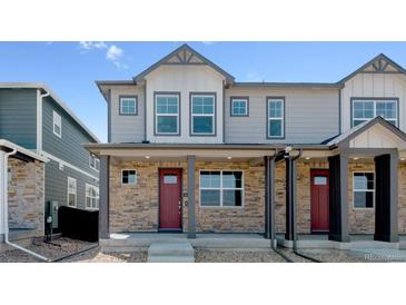 Charming townhome with stone accents, gray siding, and a welcoming front porch at 18724 E 99Th Ave, Commerce City, CO 80022