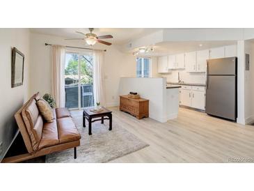 Bright living room with hardwood floors, a ceiling fan, and a sliding glass door to a balcony at 12486 W Nevada Pl # 106, Lakewood, CO 80228