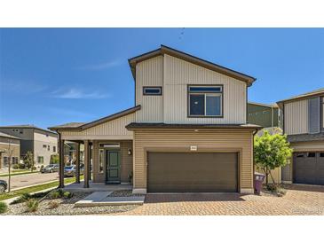 Two-story home featuring a two-car garage and a covered front porch under a clear blue sky at 19118 E 54Th Pl, Denver, CO 80249
