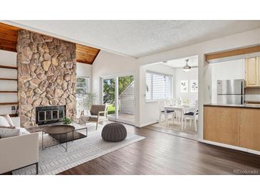 Living room with stone fireplace, hardwood floors, and access to a patio at 13609 E Yale Ave # A, Aurora, CO 80014