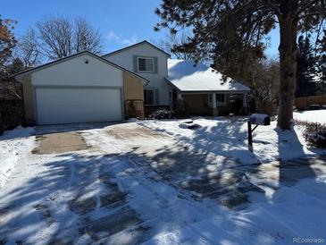 Two-story home with attached garage, covered porch, and snowy yard at 18360 E Ithaca Pl, Aurora, CO 80013