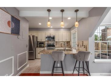 Well-lit kitchen features granite countertops, stainless steel appliances, and bar seating with decorative pendant lights at 8360 W 87Th Dr # D, Arvada, CO 80005