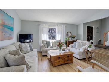 Bright living room featuring hardwood floors, large window with natural light, and comfortable seating arrangement at 3621 S Kalispell St, Aurora, CO 80013