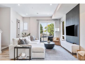 Bright living room featuring a comfortable sectional sofa, modern decor, and sliding glass doors to balcony at 9052 Harlan St, Westminster, CO 80031