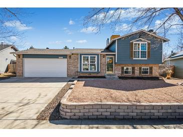 Charming bi-level home featuring brick and blue siding, complemented by a well-maintained front yard at 8622 S Everett St, Littleton, CO 80128