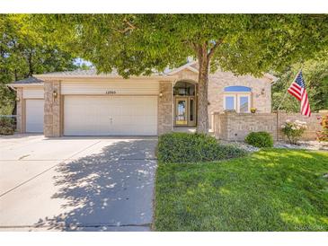 Charming brick home with a well-manicured lawn, mature tree, and American flag for a welcoming curb appeal at 12705 Kalamath Ct, Westminster, CO 80234