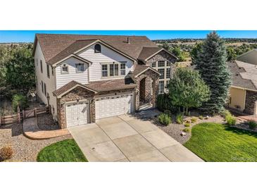 Two-story house with stone accents, three-car garage, and landscaped yard at 6017 Merchant Pl, Parker, CO 80134