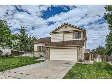 Two story tan house with beige brick siding, a two car garage, and a well maintained lawn at 9544 Josephine St, Thornton, CO 80229