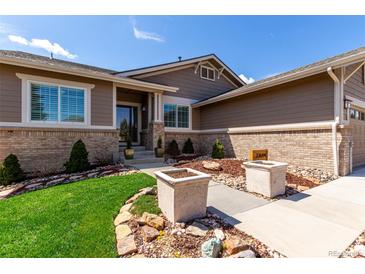 Charming home featuring a lush landscaped yard, brick accents, and a welcoming entryway at 23644 E Phillips Pl, Aurora, CO 80016