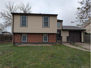Charming two-story home featuring tan siding, brick accents, and an attached one-car garage at 220 Mckinley Dr, Bennett, CO 80102