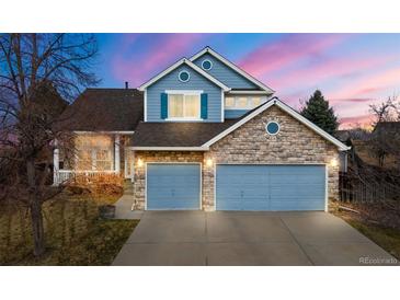 Charming two-story home featuring a stone and blue facade, three-car garage, and landscaped front yard at 5604 S Shawnee St, Aurora, CO 80015