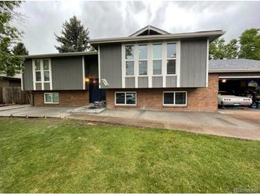 Charming split-level home with a manicured lawn, brick accents, and a spacious driveway leading to an attached garage at 4449 S Xavier St, Denver, CO 80236