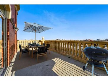 Spacious outdoor patio with dining set, umbrella, grill, and beautiful city views at 1950 N Logan St # 1109, Denver, CO 80203