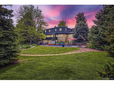 Expansive backyard featuring a pool, lush lawn, mature trees and beautiful landscaping at 6451 Crestbrook Dr, Morrison, CO 80465