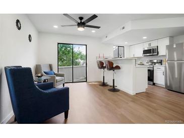 Bright living room featuring modern finishes, a breakfast bar, and sliding door access to the outside at 8701 Huron St # 2-106, Thornton, CO 80260