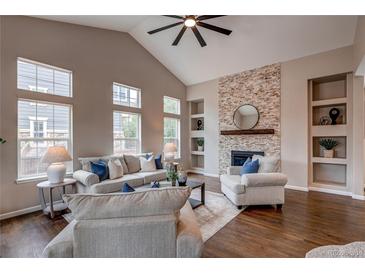 Cozy living room featuring vaulted ceiling, brick fireplace, and large windows at 5597 S Buchanan St, Aurora, CO 80016