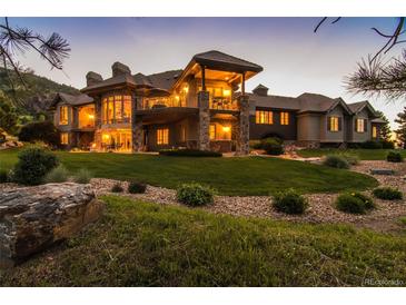 Luxury home with stone accents, expansive lawn, and mountain views at dusk at 9977 Elkhorn St, Littleton, CO 80127