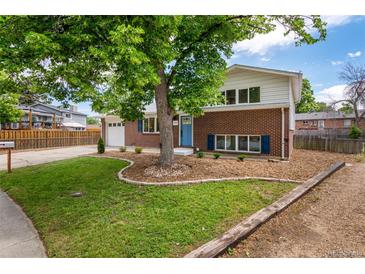 Charming two-story brick home with a well-manicured lawn, mature tree, and a bright blue front door at 1011 Yeager Dr, Longmont, CO 80501