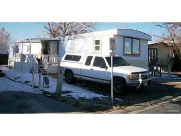 Cozy manufactured home with a small porch and an adjacent parked truck at 8533 Cook Ct # 115, Denver, CO 80229