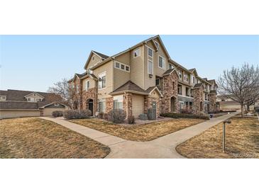 Tan three-story townhome with stone accents and landscaping at 431 Black Feather Loop # 817, Castle Rock, CO 80104